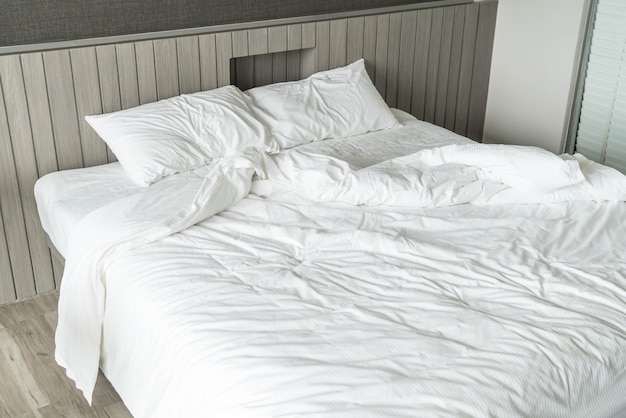 rumpled bed with white messy pillow decoration in bedroom 