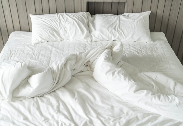 rumpled bed with white messy pillow decoration in bedroom 