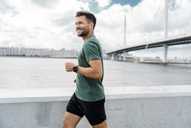 On the run Uses a fitness watch and an app Portrait of a sporty man smiling young running training