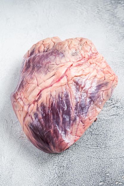 Rund- of kalfsvlees rauw hart op een slagerstafel. Witte achtergrond. Bovenaanzicht.