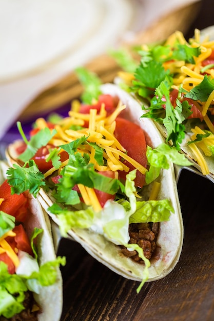 Rundergehakttaco's met romaine sla, tomatenblokjes en geraspte cheddarkaas.