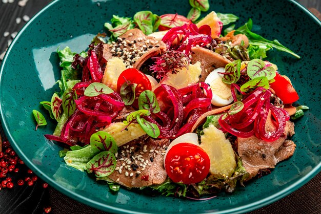 Rundertongsalade met verse groenten ingelegde uitjes en mini mais op een bord