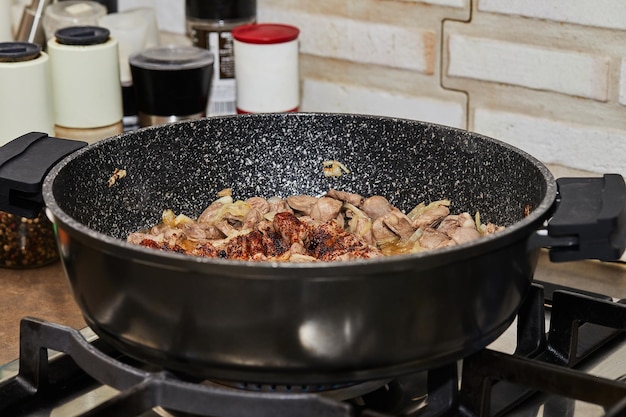 Rundvlees gebakken met uien in pan op gasfornuis