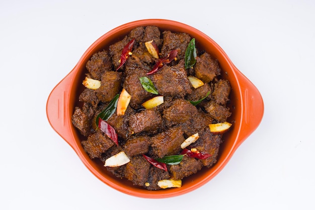 Rundvlees geroosterde masala of curry zelfgemaakte recept gerangschikt in terracotta kom met witte achtergrond