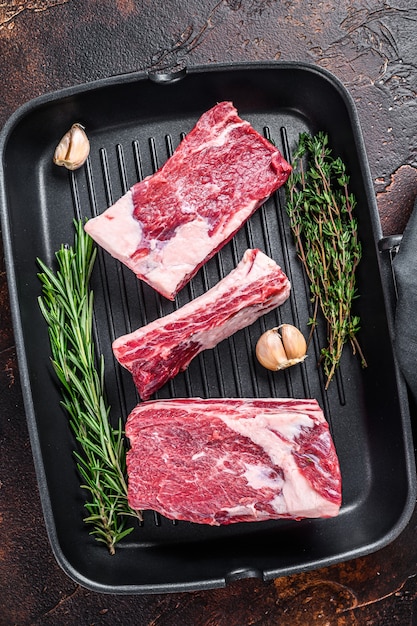 Rundvlees kalf korte ribben vlees in een grillpan klaar om te koken. donkere achtergrond. bovenaanzicht.