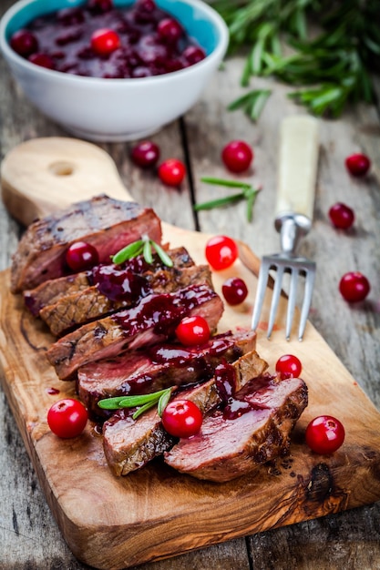 Rundvlees met huisgemaakte cranberrysaus op een rustieke achtergrond