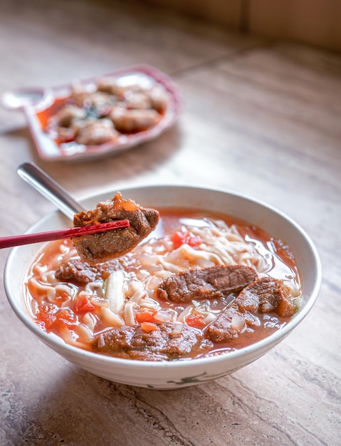 Rundvlees noodle Taiwan ramen maaltijd met tomatensaus bouillon in kom op heldere houten tafel beroemde Chinese stijl eten close-up bovenaanzicht kopieerruimte