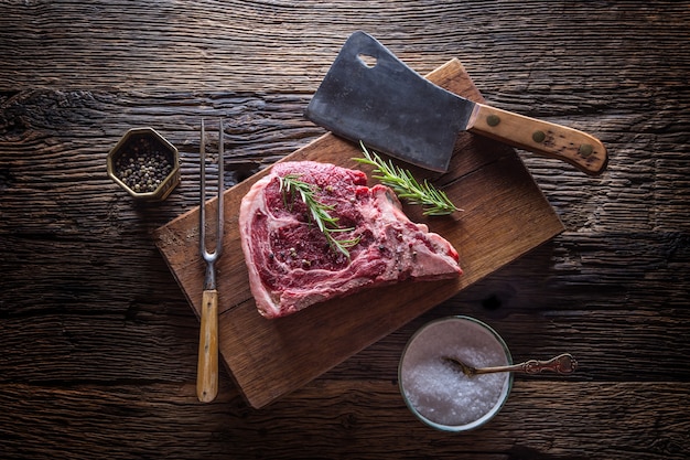 Rundvlees rauwe biefstuk. Rauwe verse T-bone steak met zoute peper en rozemarijn.