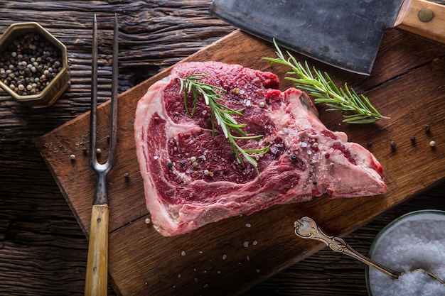 Rundvlees rauwe biefstuk. Rauwe verse T-bone steak met zoute peper en rozemarijn.