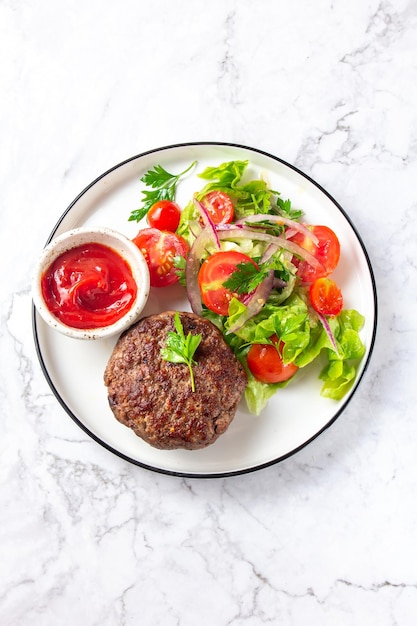 Rundvleeshamburger met slatomatensalade op wit plaatbovenaanzicht