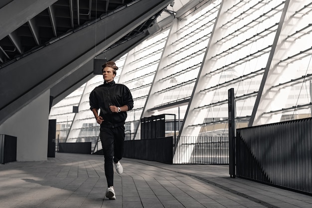 Foto l'atleta del corridore sta correndo vicino allo stadio. concetto di benessere di allenamento jogging uomo.