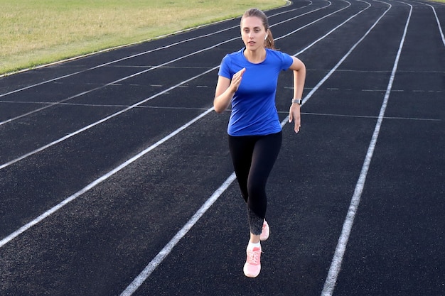 Foto runner-atleet die op atletiekbaan loopt en haar cardio in het stadion traint. joggen in hoog tempo voor de concurrentie.