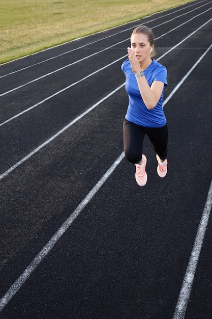 Runner-atleet die op atletiekbaan loopt en haar cardio in het stadion traint. Joggen in hoog tempo voor de concurrentie.