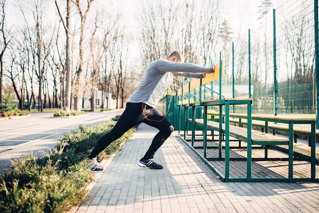 Runner doing stretching exercise before jogging. Jogger on morning fitness workout. Athlete in sportswear, fitness training outdoor
