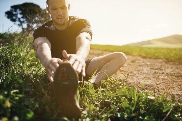 Runner grass or man stretching legs for training exercise or fitness workout in countryside nature Muscle warm up healthy or sports athlete ready to start practice for wellness body or running
