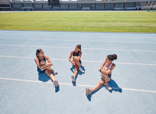 Foto runner groep vrouwen en strekken op de grond voor fitness praten of sport in training training of oefening running team atleet vrouw en diversiteit in gesprek op sportveld voor warming-up in de zon