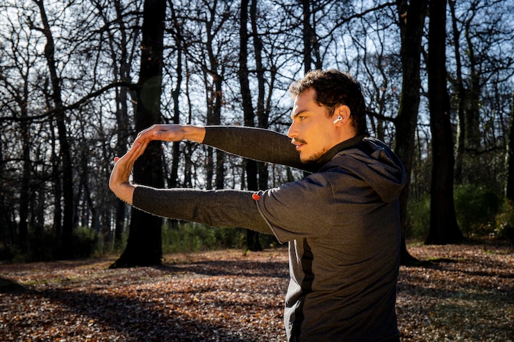Photo runner is doing stretching in the woods man with blue eyes and mustache is training in the park