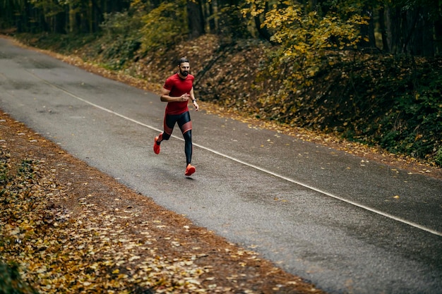 Photo a runner is running on roadway in forrest on rainy weather