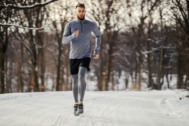 Runner joggen in de natuur in de winter op sneeuwweer.