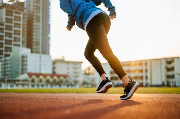 Runner jogging in sun lightAsian woman fitness model training in the morning at sport stadium in the cityJoggingRunning Healthy and lifestyle concepts