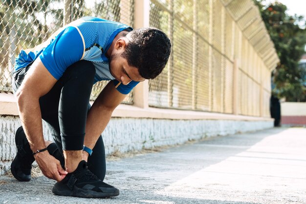 Runner man koppelverkoop schoen of sneakers veters op straat met kopieerruimte