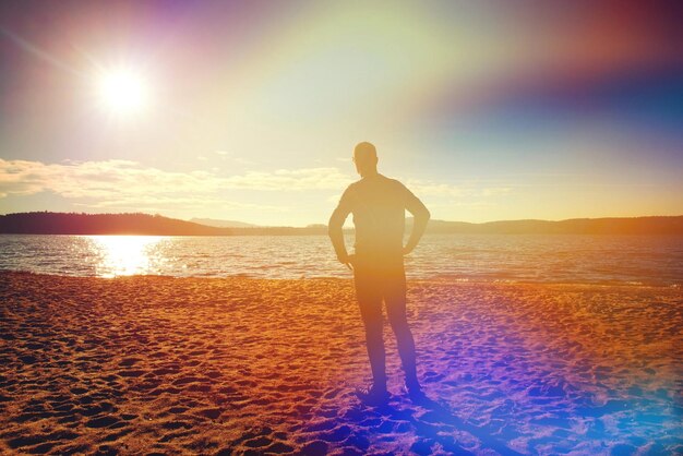 Runner man stand for deep breath moment whithin regular morning run on the beach