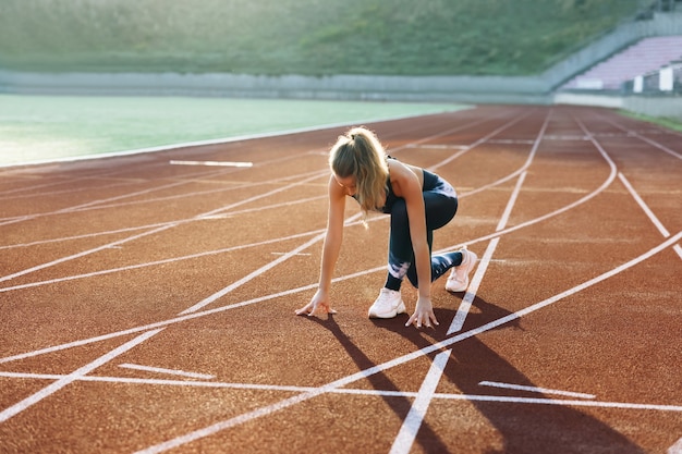 Runner opstijgen vanaf de startblokken op atletiekbaan jogger activiteit atleet sportvrouw