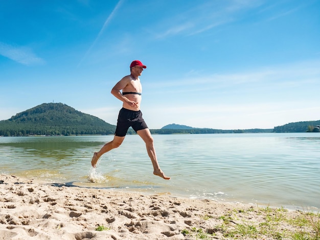 Runner run in water at beach drops refreshing his body runner with heart rate monitor smart watch