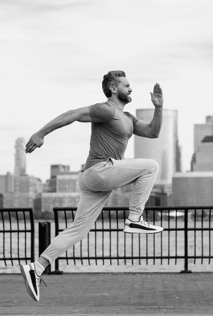 Бегун Бегущий мужчина бегает на улице Зрелый мужчина бегун и фитнес-спортивные модели тренируются на открытом воздухе недалеко от Манхэттена в Нью-Йорке Тысячелетний спортсмен бегает во время спортивных тренировок на улице