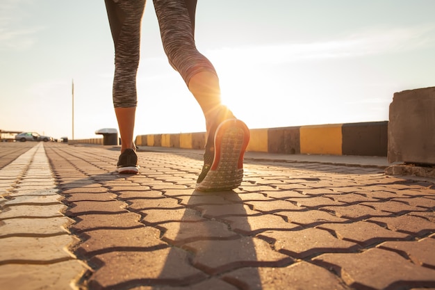 Runner voeten lopen op weg close-up op schoen. vrouw fitness zonsopgang joggen workout wellness concept.