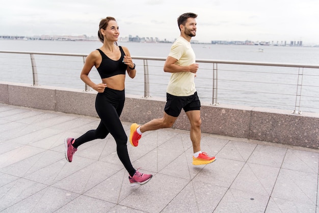 Runners are a man and a woman in sportswear and running shoes in full height Athletes