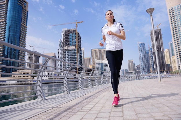 Бег в городском парке. Женщина-бегунья бегает утром на улице на фоне городской сцены Дубая
