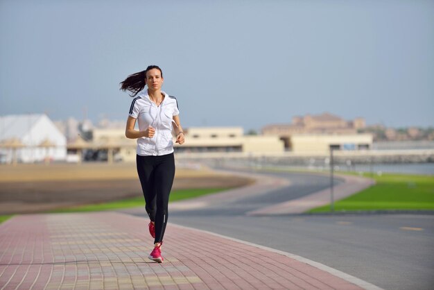 Running in city park. Woman runner outside jogging at morning with Dubai urban scene in background