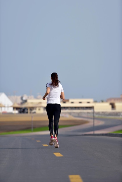 Running in city park. Woman runner outside jogging at morning with Dubai urban scene in background