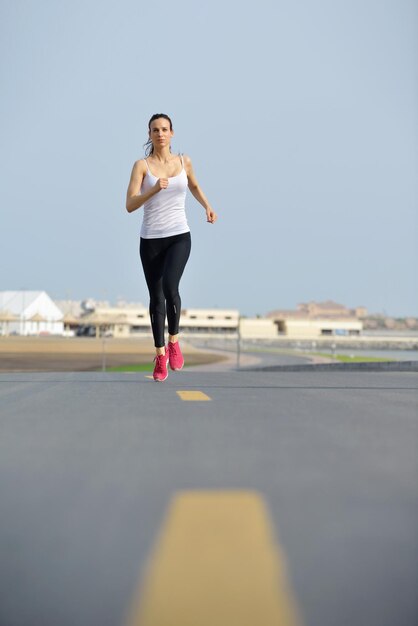 Running in city park. Woman runner outside jogging at morning with Dubai urban scene in background