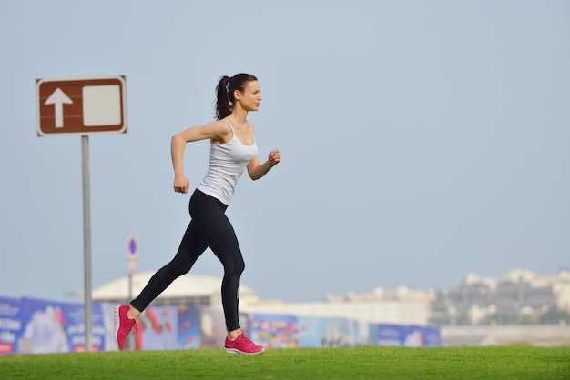 Running in city park. Woman runner outside jogging at morning with Dubai urban scene in background