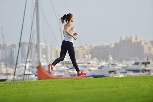 Running in city park. Woman runner outside jogging at morning with Dubai urban scene in background