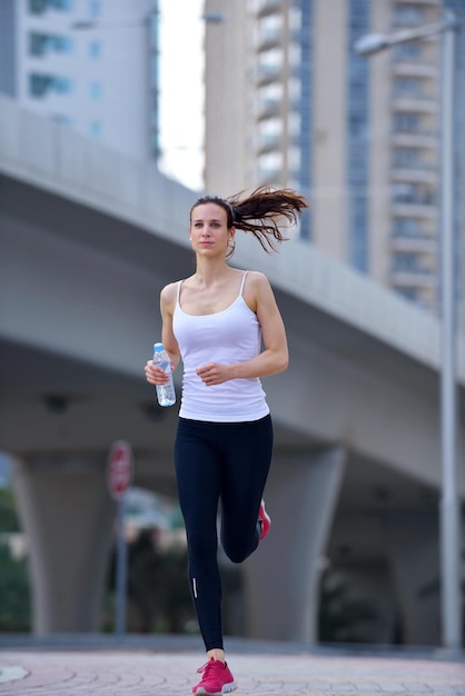 Бег в городском парке. Женщина-бегунья бегает утром на улице на фоне городской сцены Дубая