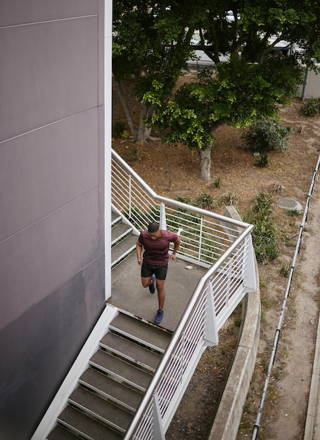 Running fitness and training with man on stairs for sports workout and cardio endurance Mindset challenge and focus with runner on steps of building for speed exercise and sports marathon