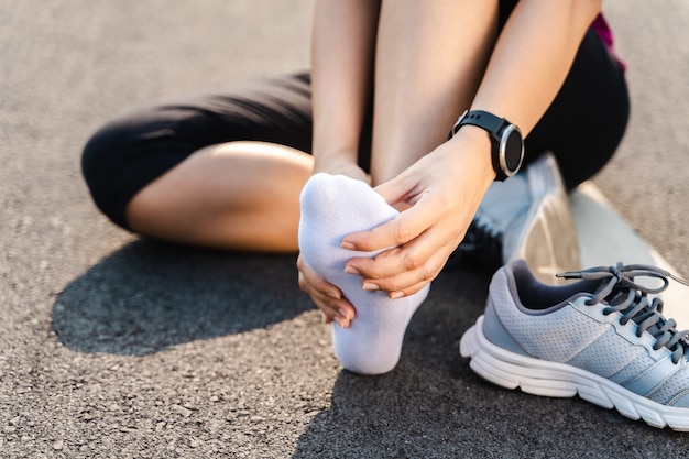 달리기 부상 다리 사고 - 고통스러운 염좌된 발목을 잡고 다치는 스포츠 여성 주자. 관절이나 근육통이 있고 하체에 통증을 느끼는 여성 운동선수.