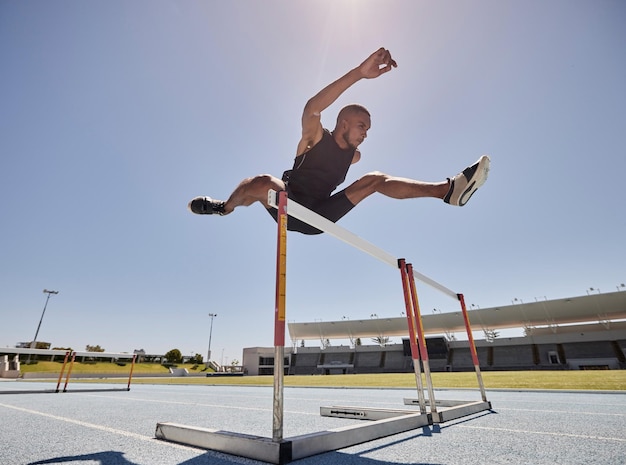 写真 スタジアムでのスピードエクササイズマラソンまたはランナートレーニングのためのランニングジャンプとアスリートハードル ショートヘルスカーディオと男性は、ジャンプ競技またはスポーツウェルネスのためのフィットネストレーニングのために速く走ります