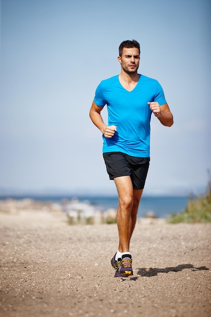 Running keeps me fit Shot of a handsome young man running on the beach