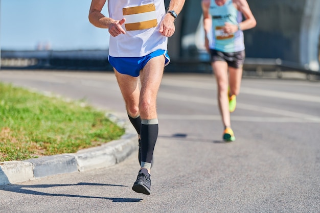 ランニングマン。都市の道路でスポーツウェアでジョギングする運動男。ストリートマラソンレース、屋外で全力疾走。健康的なライフスタイル、フィットネススポーツの趣味。