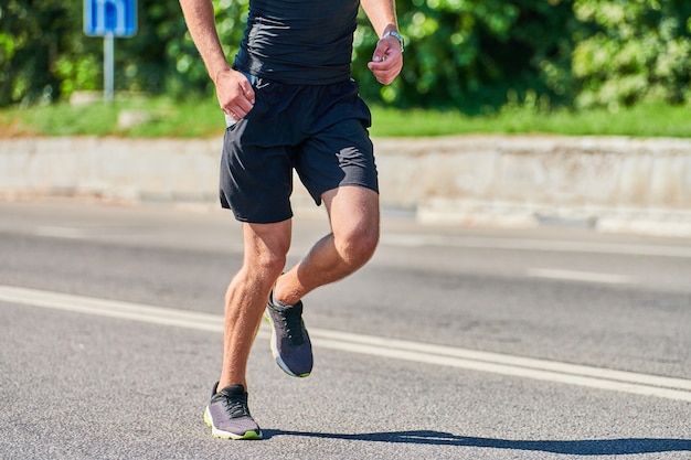 Running man. Athletic man jogging in sportswear on city road