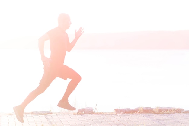 Бегущий человек Молодой спортсмен бегает трусцой на открытом воздухе