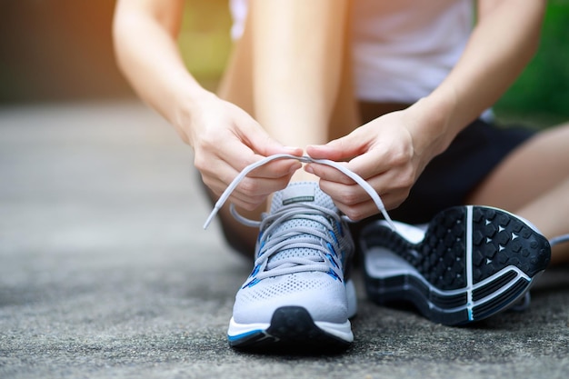 Running shoes close up female athlete tying laces for jogging\
on road runner ties getting ready for training sport lifestyle copy\
space banner