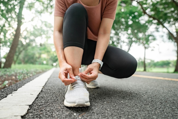 森林公園で夏の実行のためのひもを結ぶランニング シューズ ランナー女性