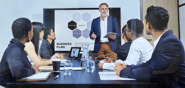 Photo running through some highlights of the topic shot of a mature businessman using a digital tablet during a presentation to his colleagues in an office