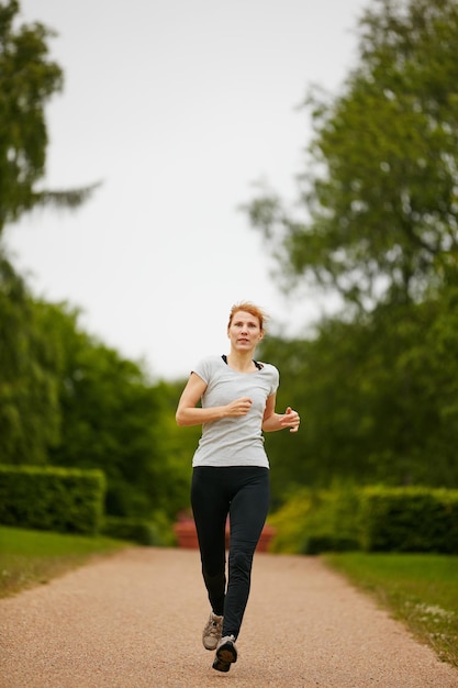 Бег к своим целям в фитнесе Снимок женщины, бегущей по тропинке в парке