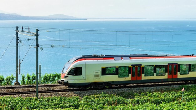 Бегущий поезд на пешеходной тропе Lavaux Vineyard Terraces возле Женевского озера и альпийских гор, район Лаво-Орон, Швейцария